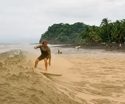Surfer carrying a board across the sand at Playa Venao